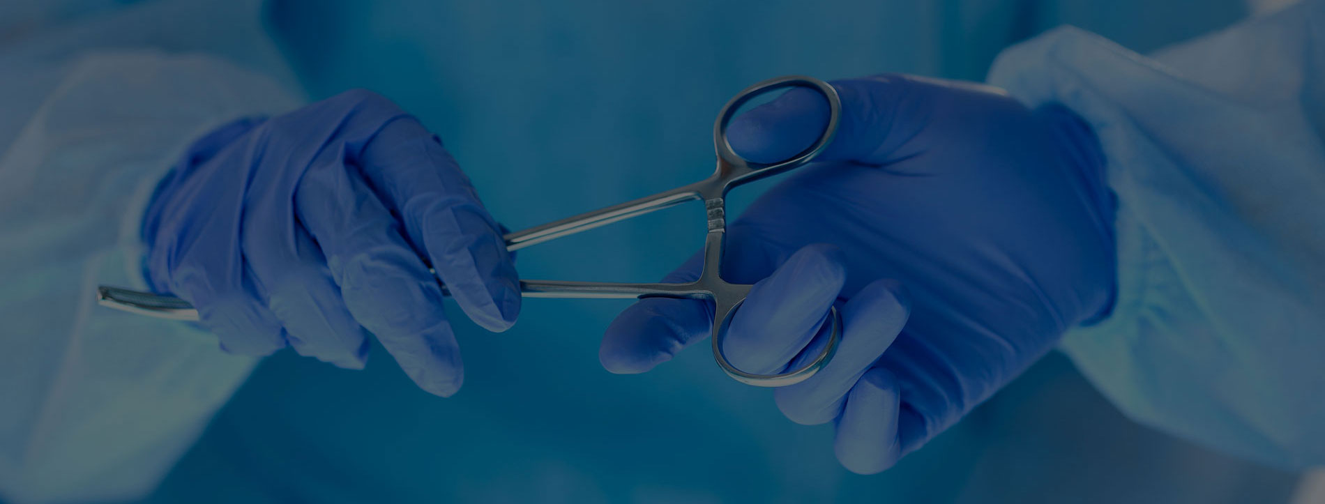 Doctor handing off a pair of surgical scissors during a cosmetic surgery procedure